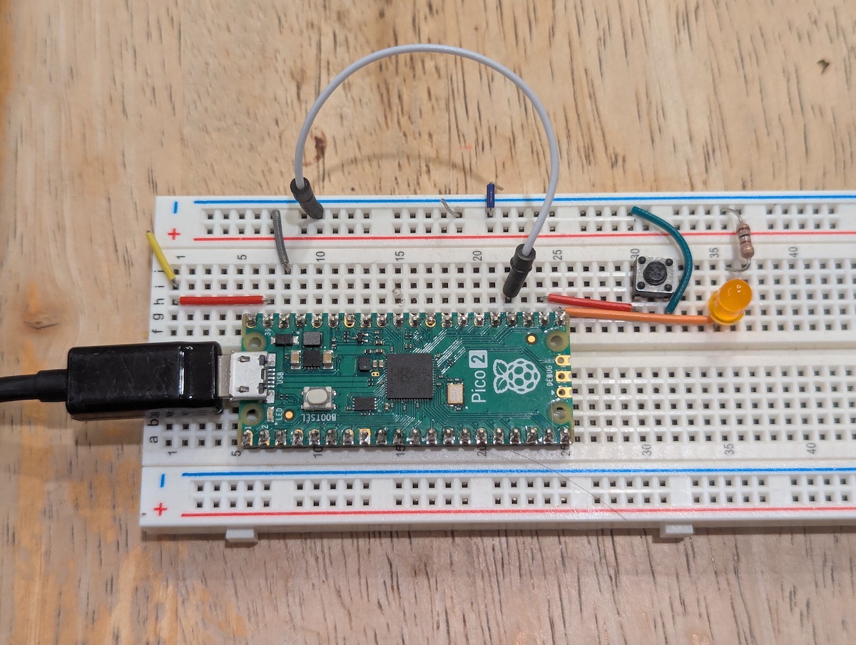 Pico2 board wired with a button and an led